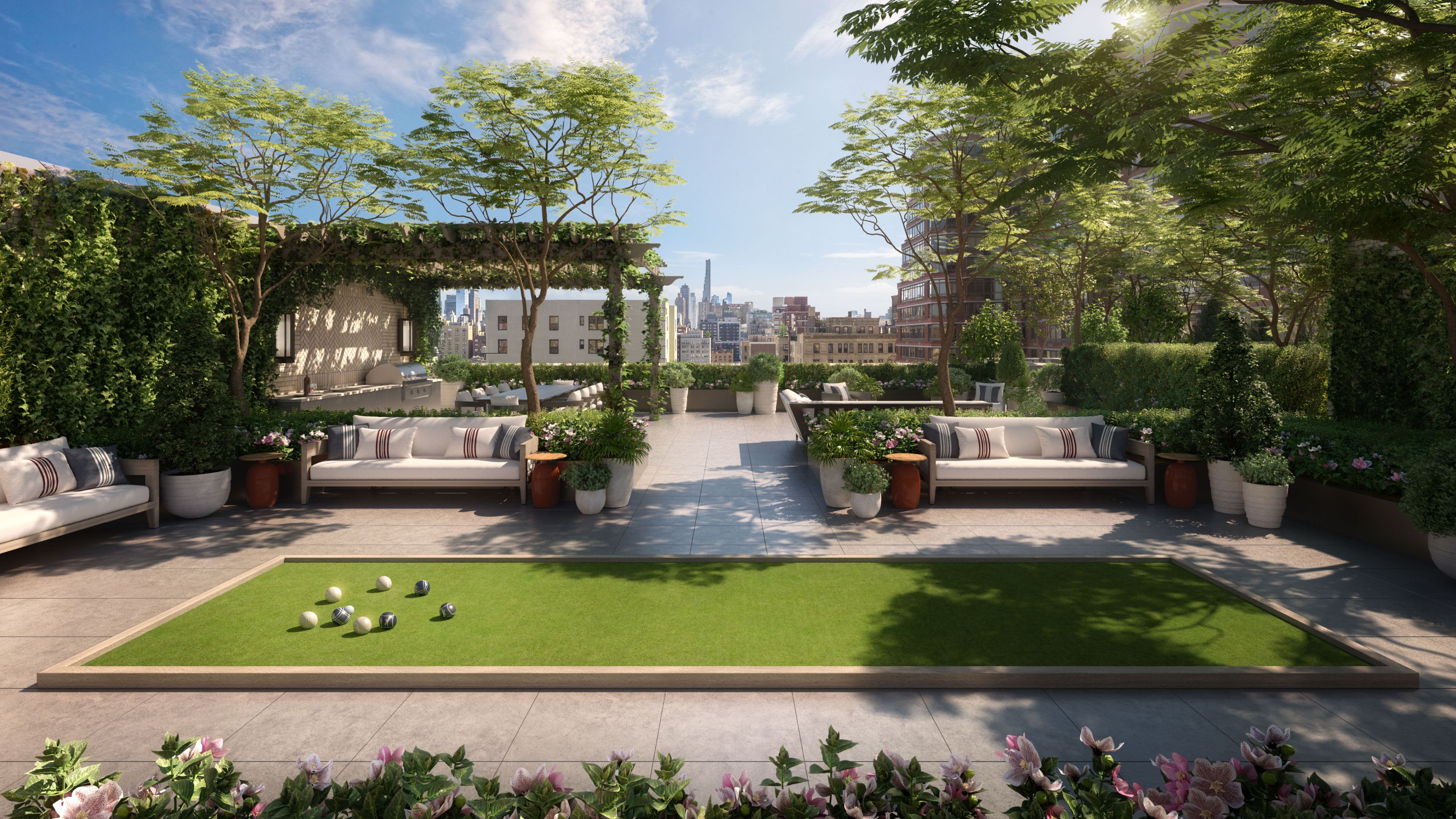 An elegant rooftop garden with a green lawn, couches, and flourishing garden at The Henry Condominiums, UWS new development.