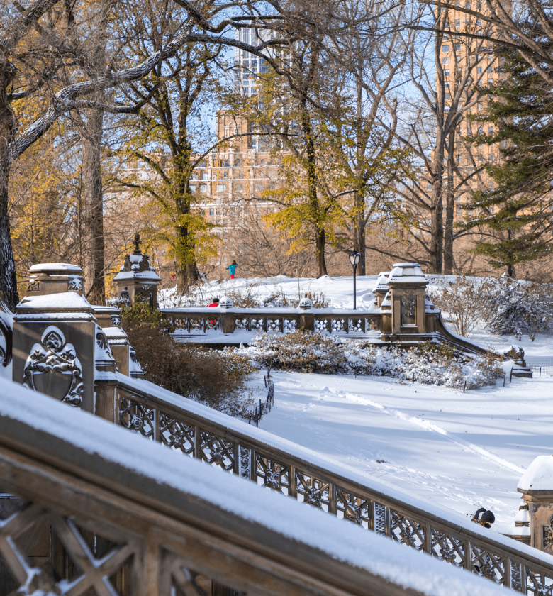 A snowy view of Bethesda Terrace in Central Park, surrounded by winter scenery near The Henry Residences in UWS at 211 W 84.