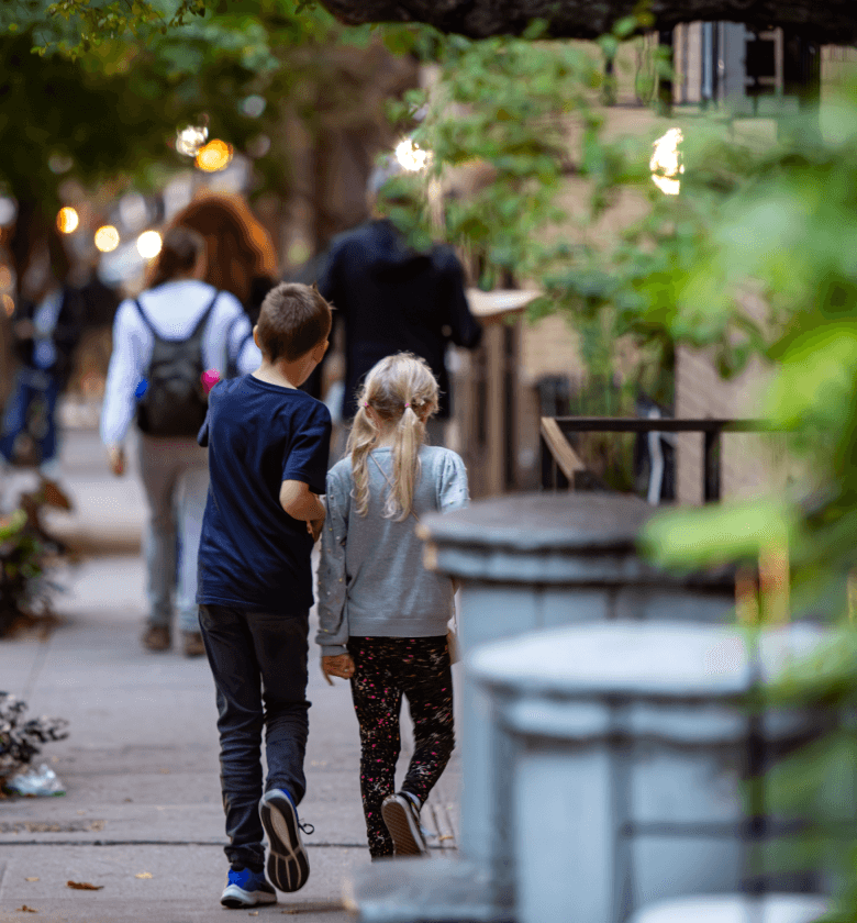 Two children walking down sidewalk together near The Henry Residences on the Upper West Side in NYC.